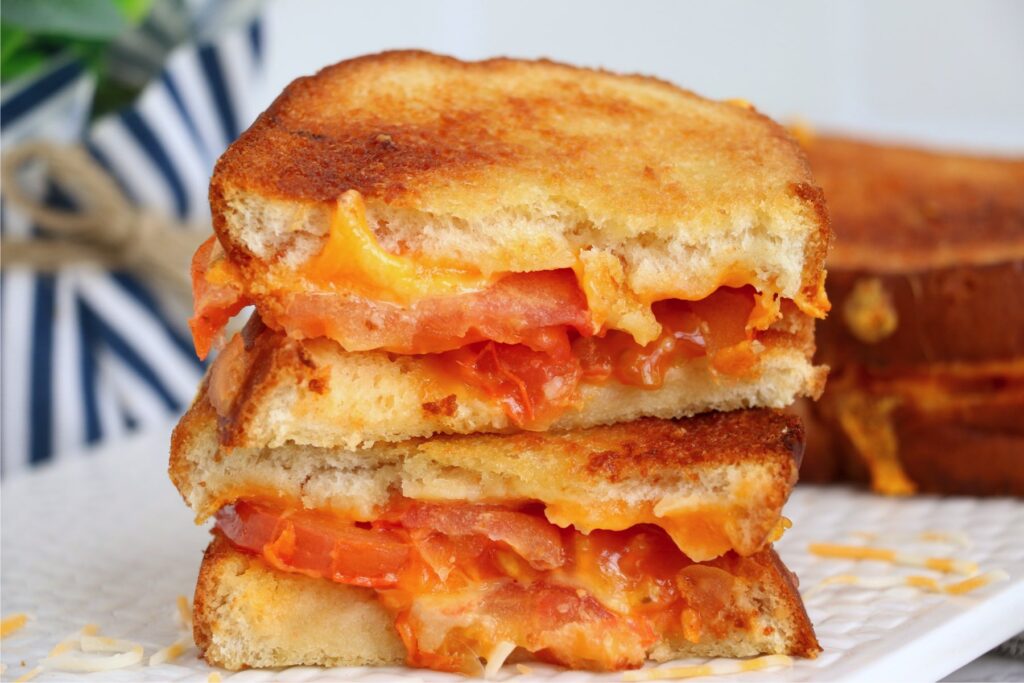 Slices of air fryer grille cheese and tomato sandwich stacked atop one another