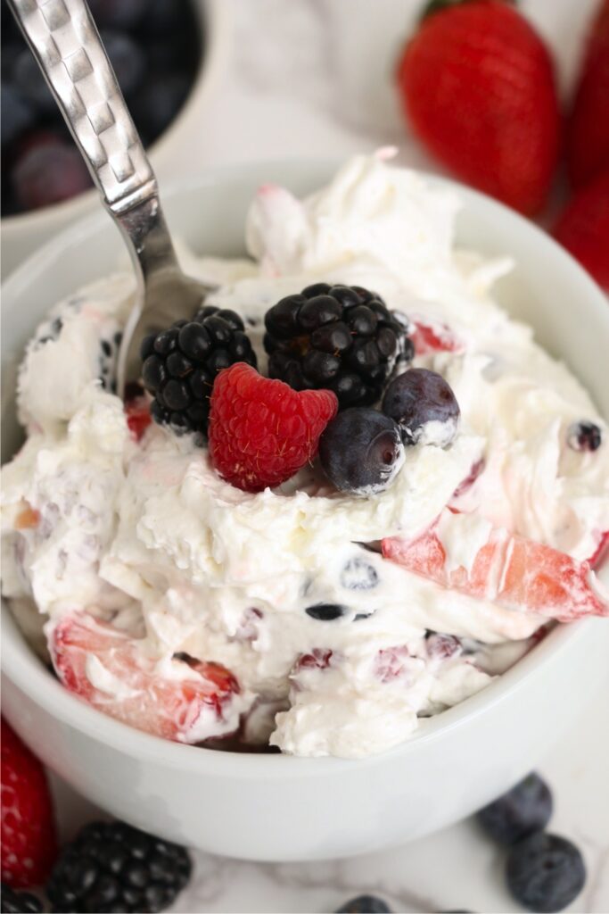 Spoon stuck in a bowlful of berry cheesecake salad