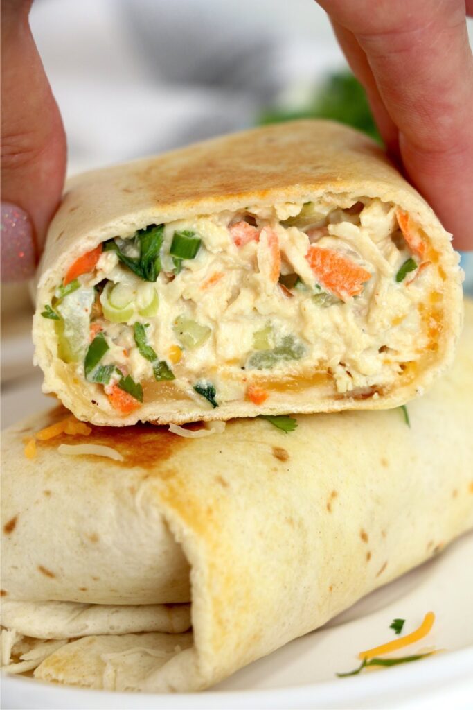 Closeup shot of chicken salad wraps stacked atop one another with the top one cut in half.