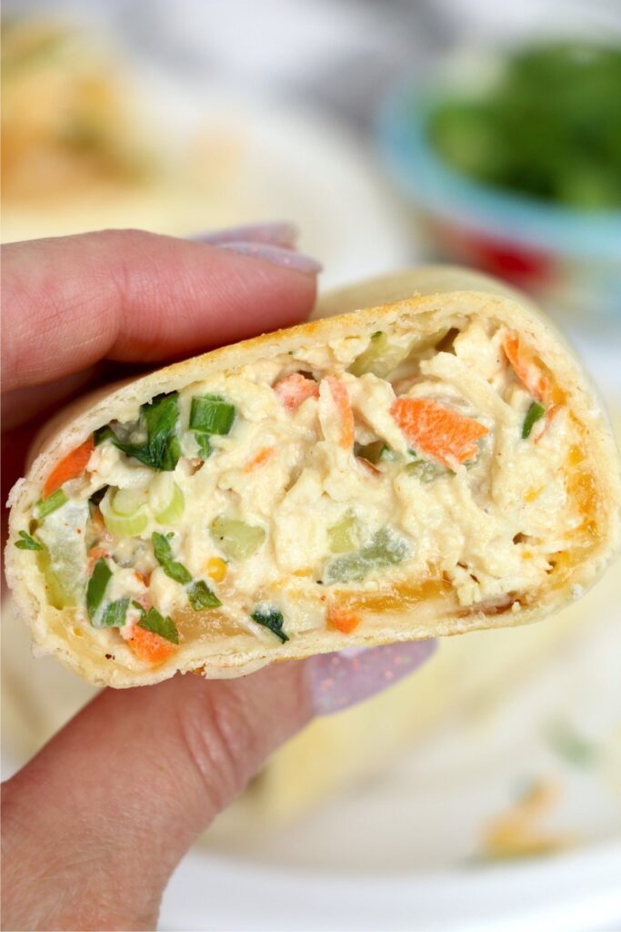 Closeup shot of hand holding a chicken salad wrap cut in half.