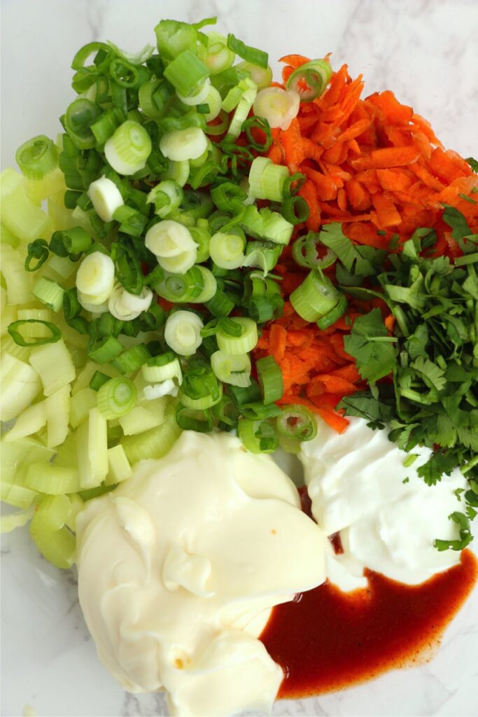 Overhead shot of veggies, mayo, and hot sauce in bowl