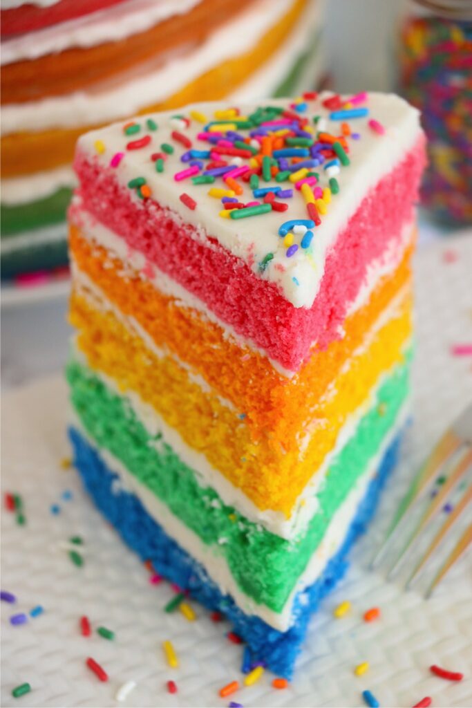 Slice of naked rainbow cake on plate