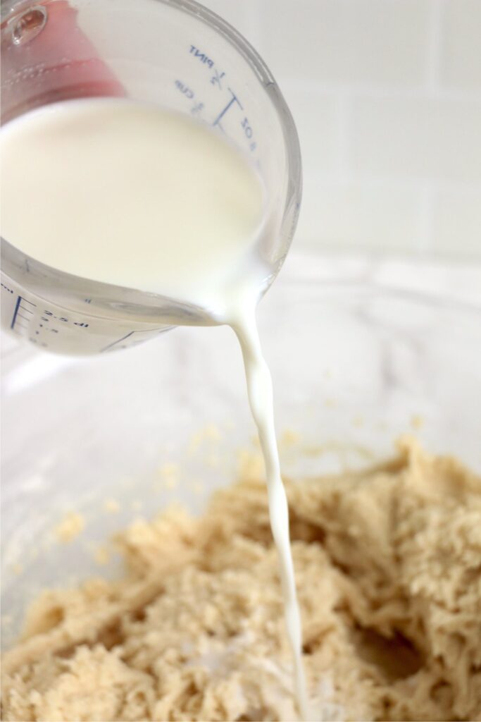 Milk being poured into cake ingredients in bowl