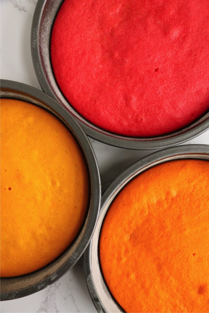 Overhead shot of baked red, orange, and yellow cakes