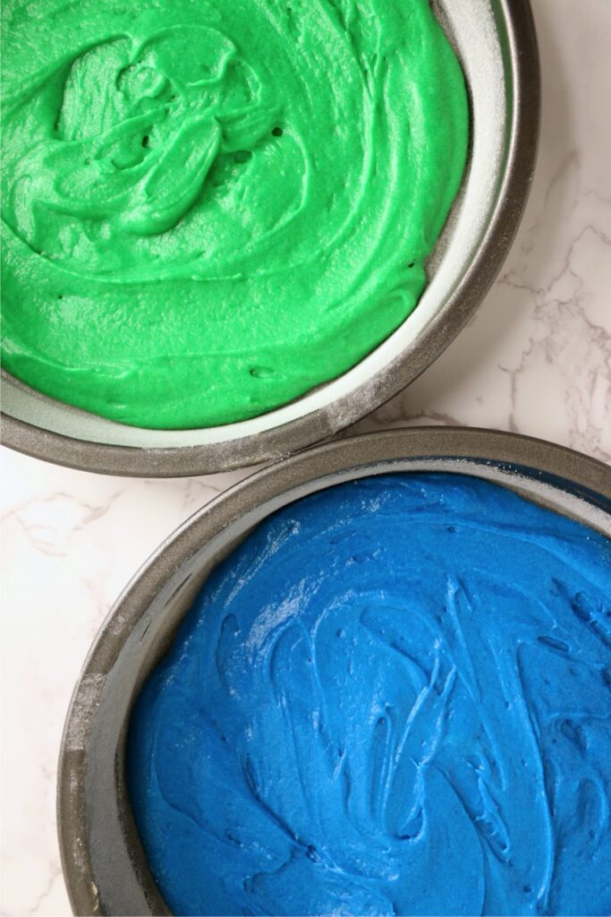 Overhead shot of green and blue cake batter in separate cake pans