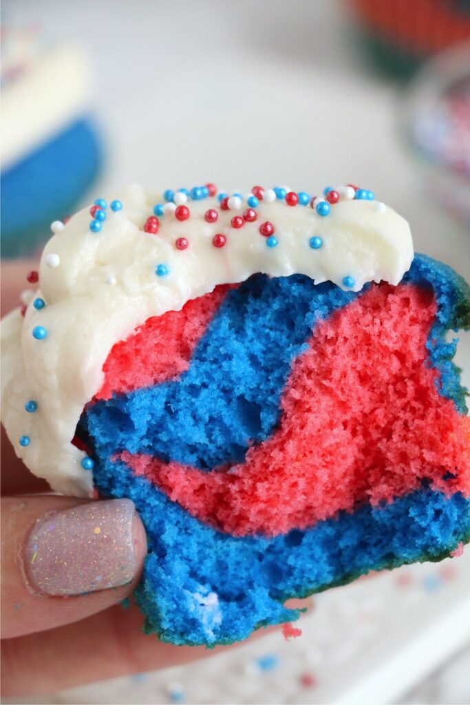 Closeup shot of hand holding a red white and blue cupcake cut in half