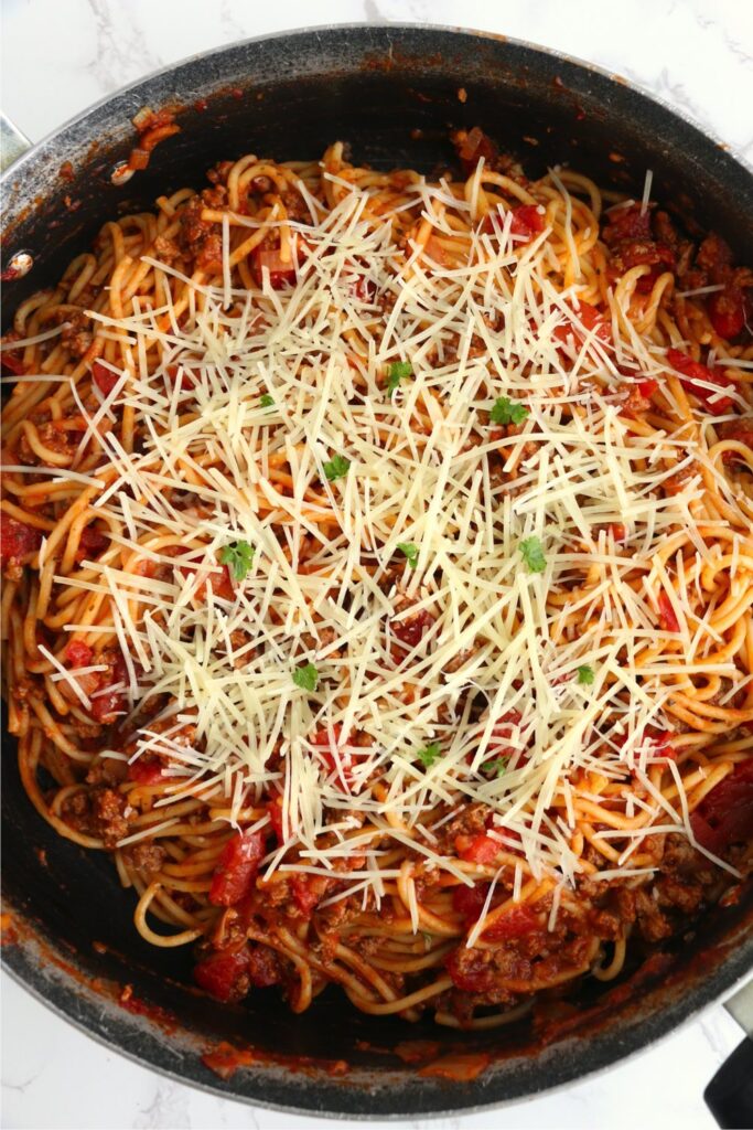 Overhead shot of school cafeteria spaghetti topped with cheese in skillet