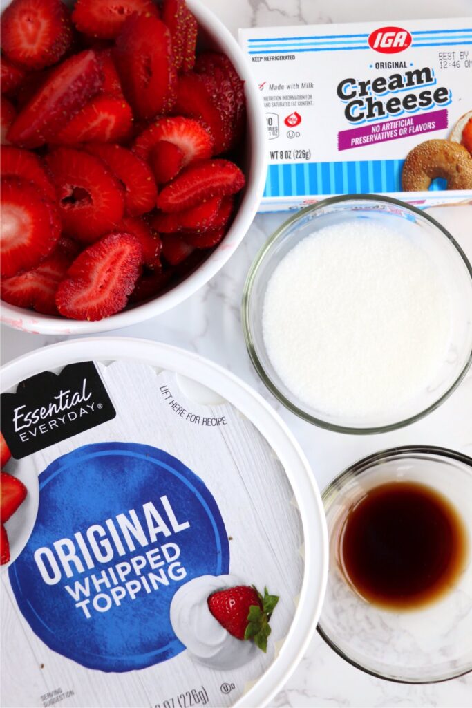 Overhead shot of individual strawberry cheesecake salad ingredients on table