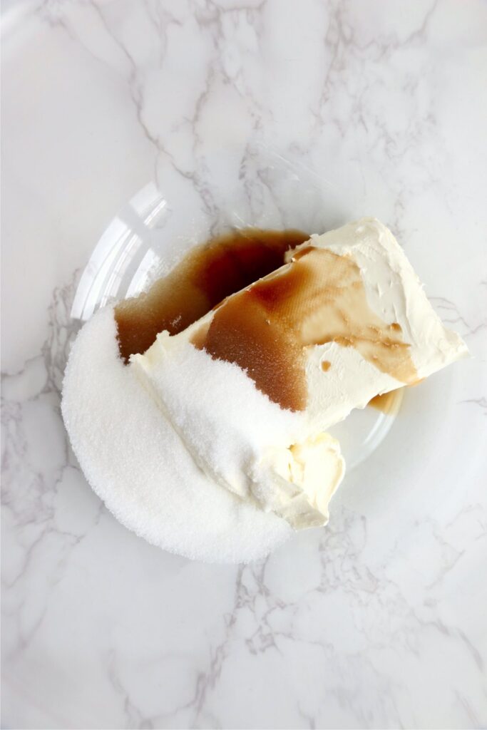 Overhead shot of cream cheese, sugar, and vanilla in bowl