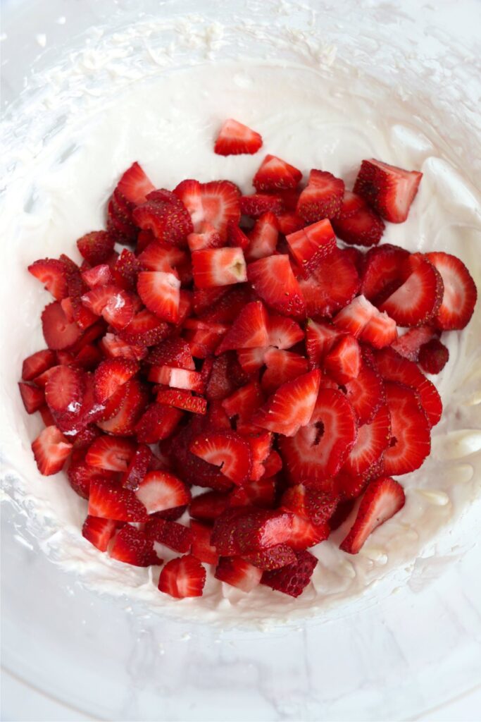 Overhead shot of sliced strawberries in cream cheese Cool Whip mixture in bowl