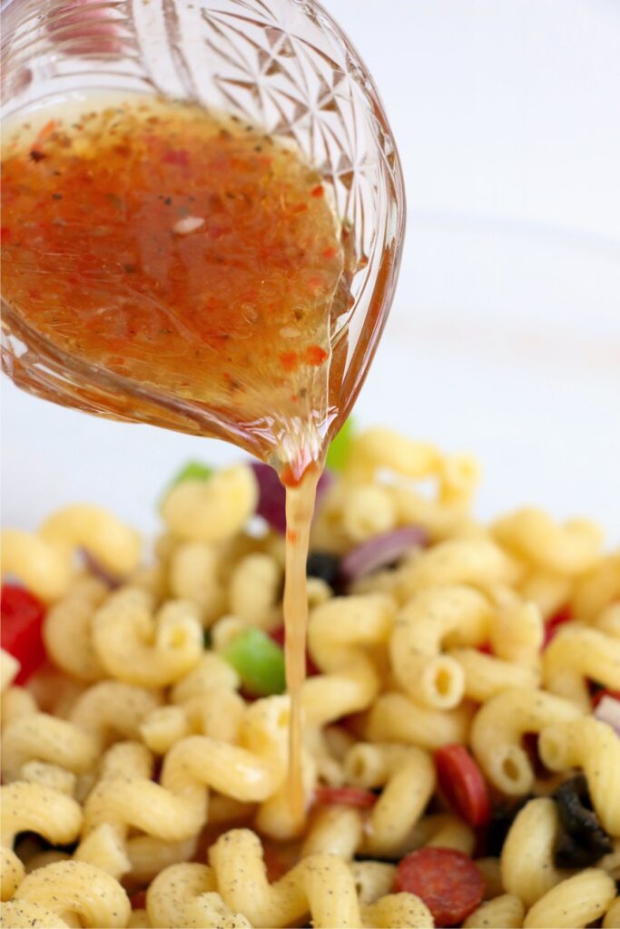 Closeup shot of Italian dressing being poured over pasta salad