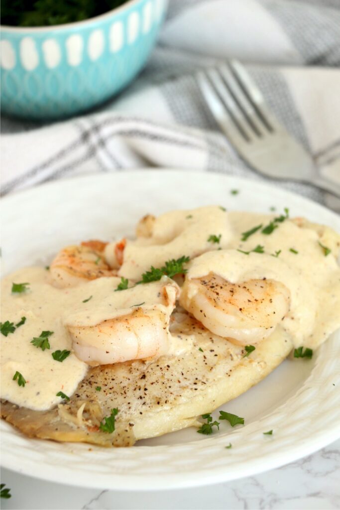 Tilapia and shrimp with sauce on plate