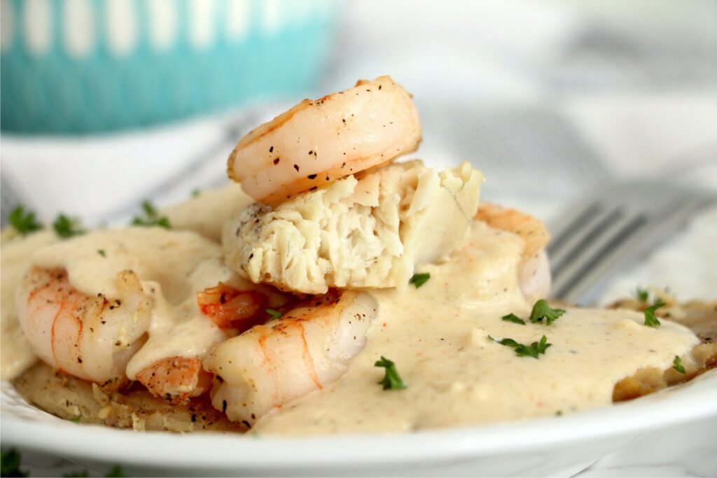 Closeup shot of tilapia and shrimp with sacue on plate