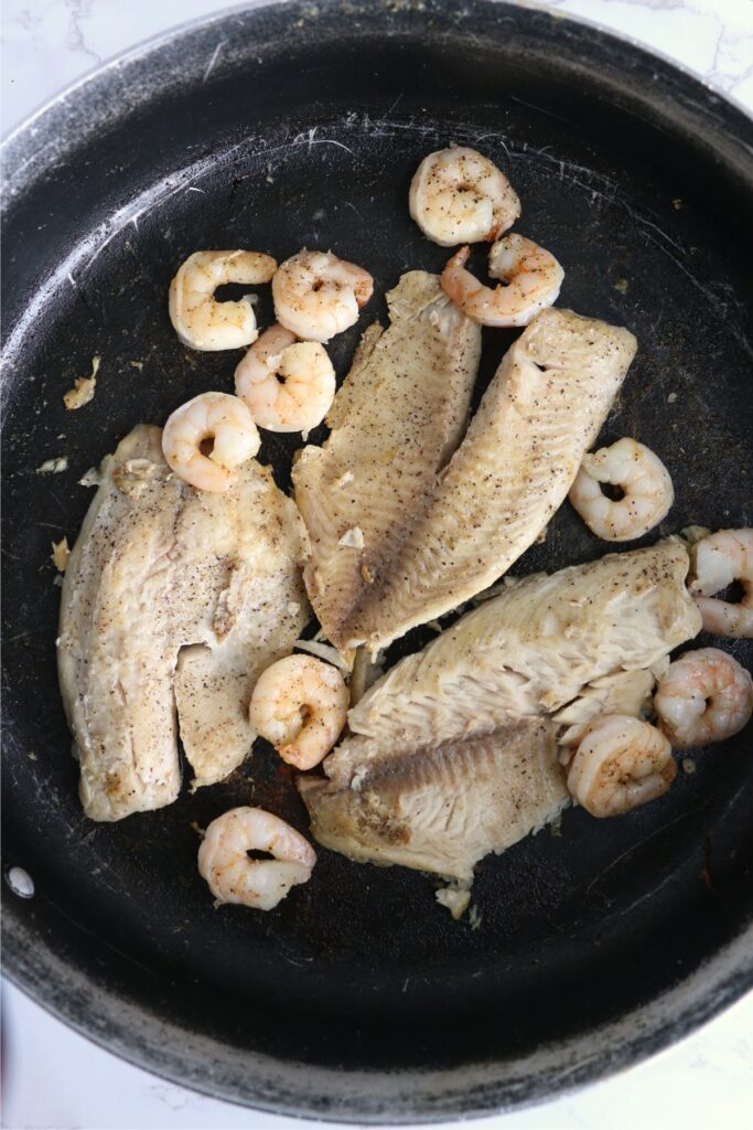 Overhead shot of cooked tilapia and shrimp in pan