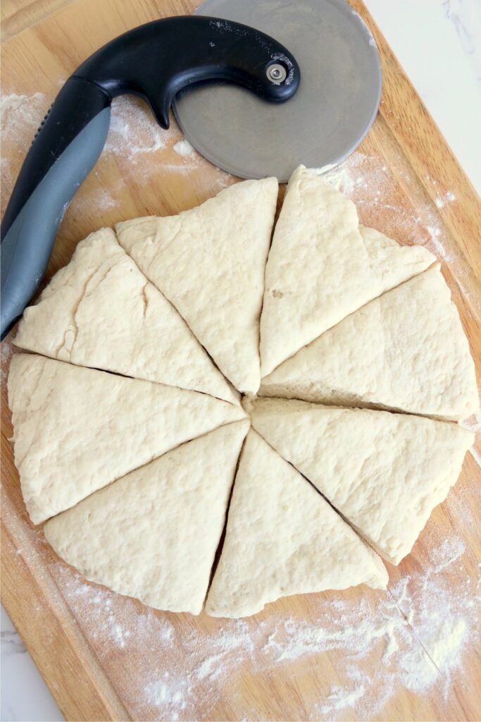Overhead shot of flattened flatbread dough cut into 8 wedges