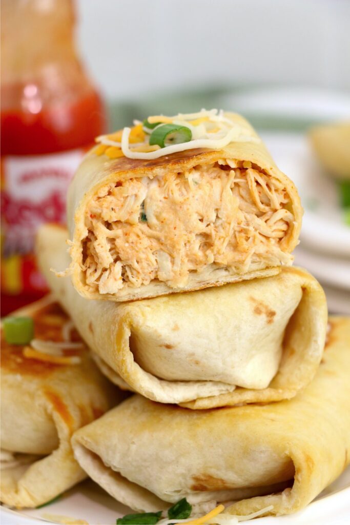 Closeup shot of stack of Buffalo chicken wraps with top wrap cut in half