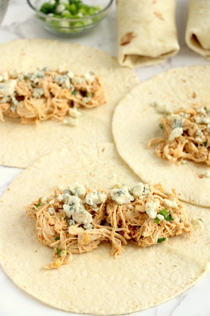 Buffalo chicken wraps filled with chicken salad and ready to be rolled up