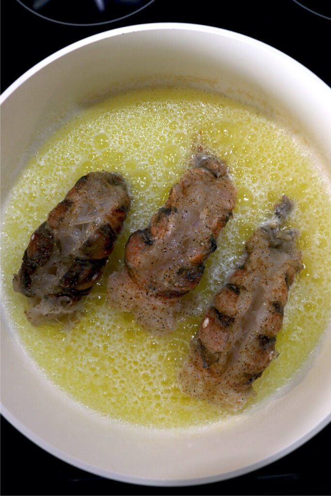 Overhead shot of lobster tails in butter poaching liquid