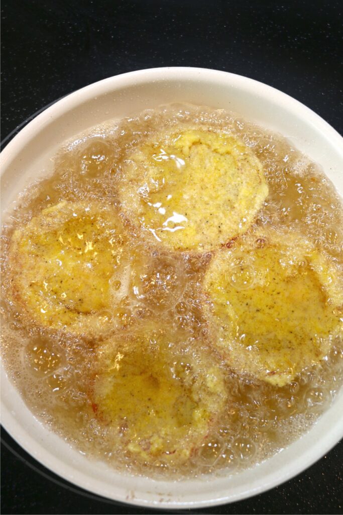 Overhead shot of battered tomato slices being fried