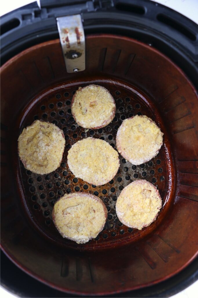 Overhead shot of battered tomato slices in air fryer basket