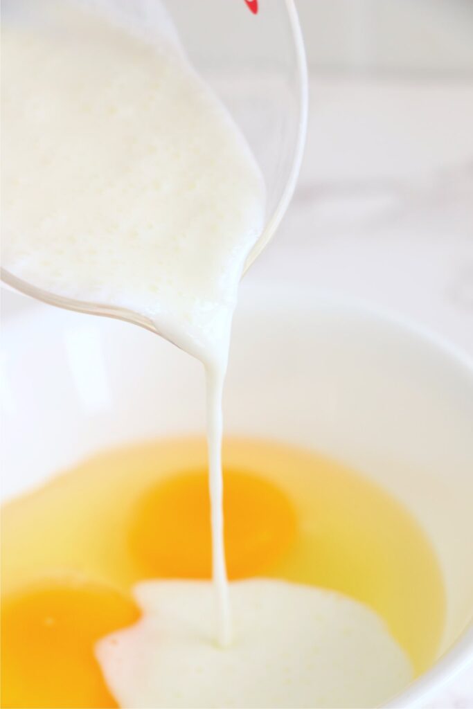 Closeup shot of buttermilk being poured into bowl with eggs