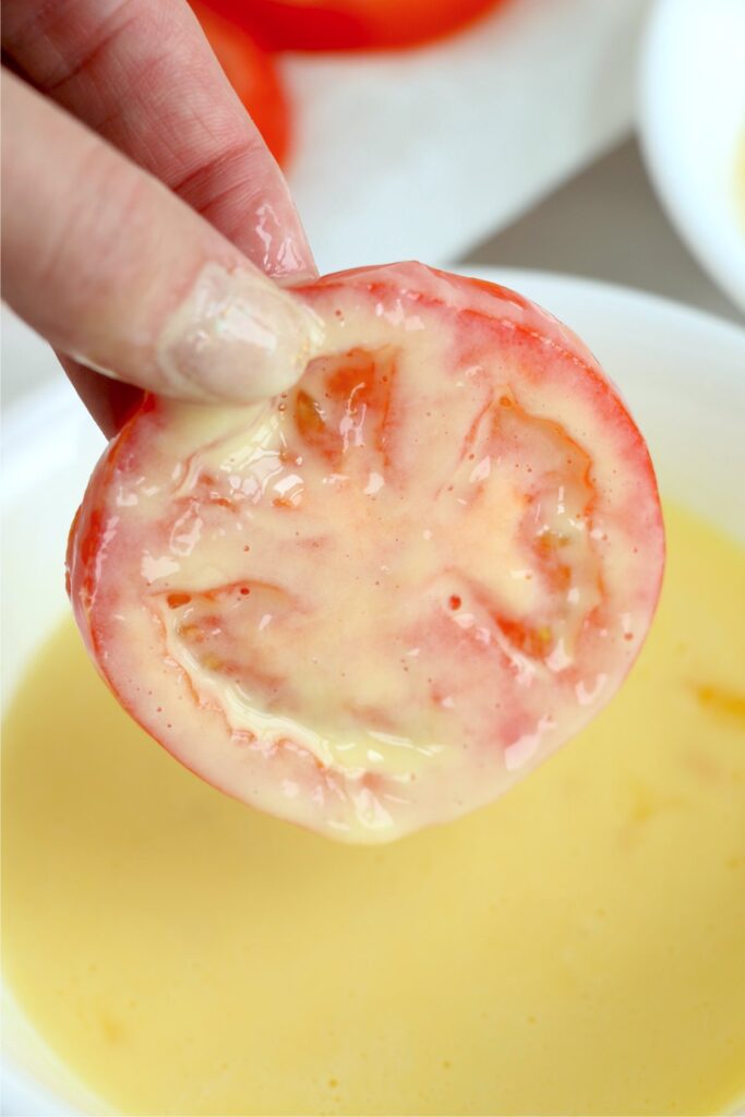 Closeup shot of red tomato slice dipped in egg mixture