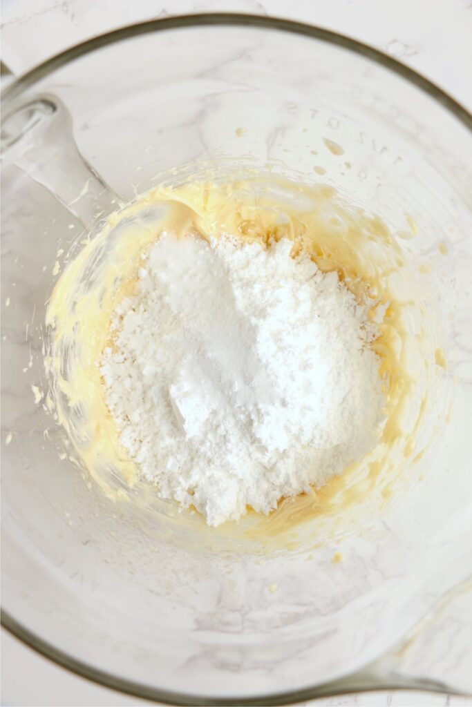 Overhead shot of powdered sugar with creamed butter in bowl