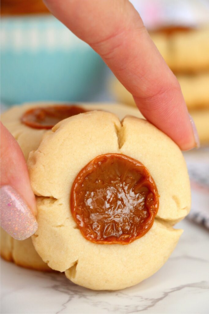 Closeup shot of fingers holding up a dulce de leche cookie