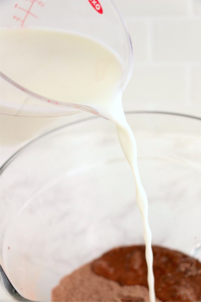 Milk being poured into glass bowl with chocolate pudding mix