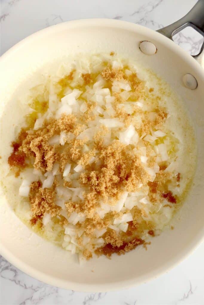 Overhead shot of melted butter, diced onions, and brown sugar in skillet