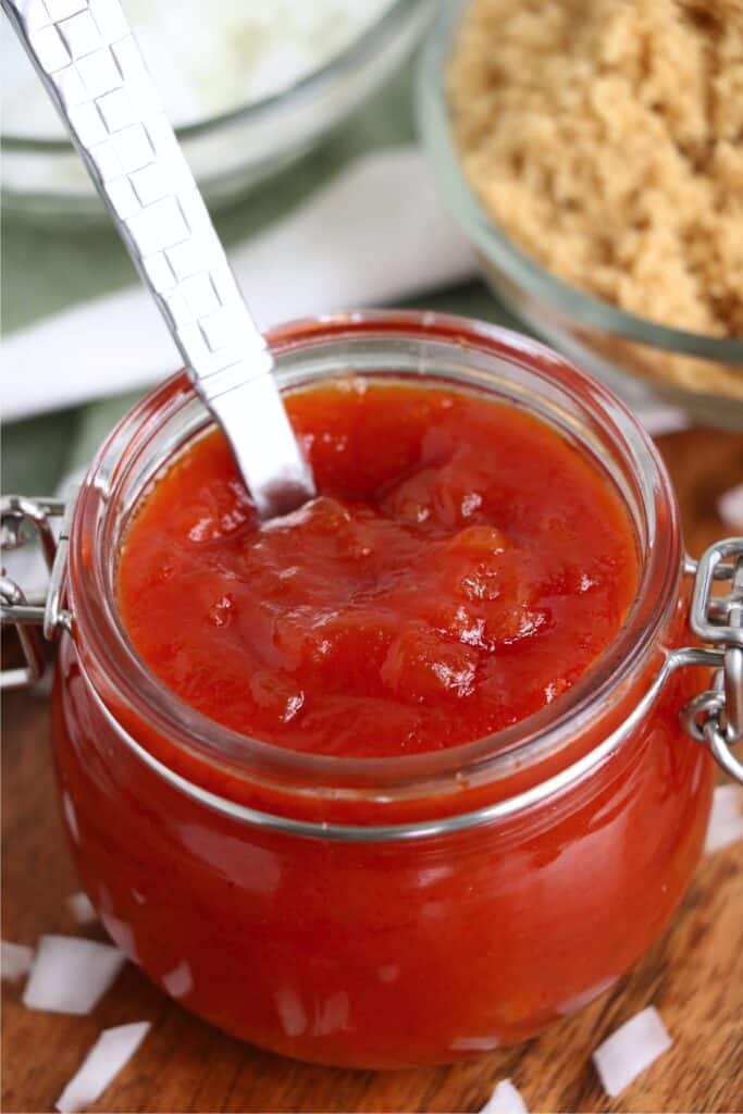 Closeup shot of spoon in jar filled with onion ketchup