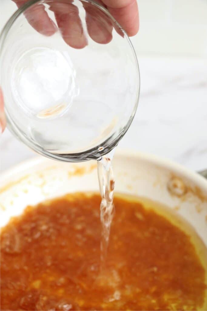 White vinegar being poured into skillet