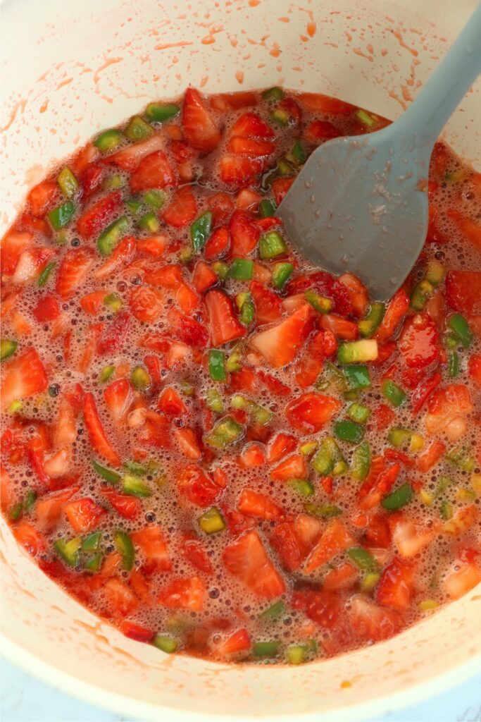 Spatula stirring jam ingredients in pot