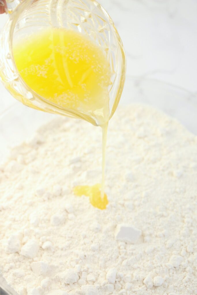 Closeup shot of butter being poured into bowl of flour and salt