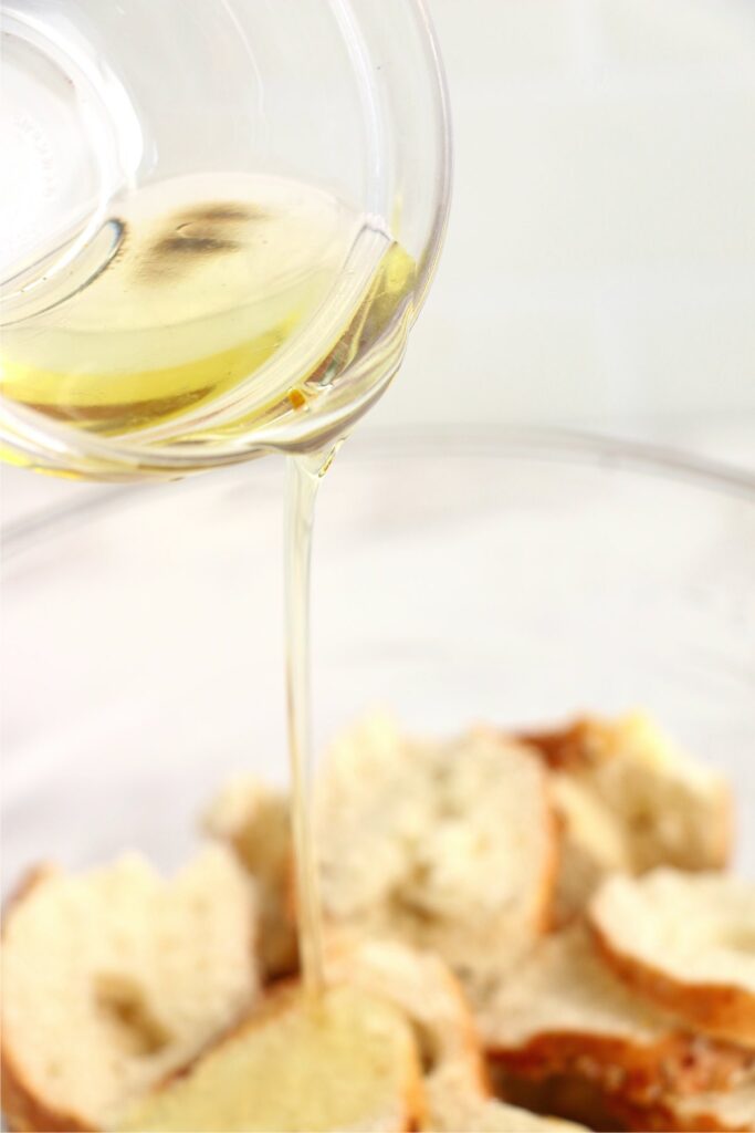 Closeup shot of olive oil being poured over bagel slices