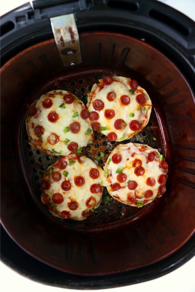 Overhead shot of air fryer English muffin pizzas in air fryer basket
