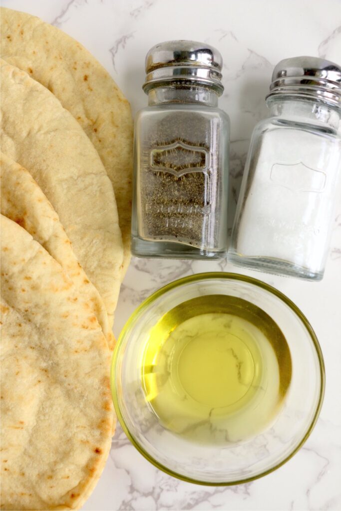 Overhead shot of pitas next to bowl of olive oil and salt and pepper shakers