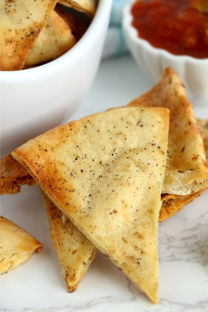 Closeup shot of air fryer pita chips next to bowl of more pita chips