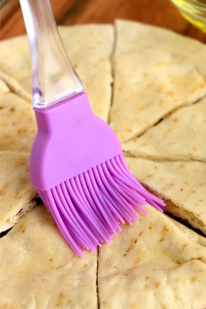 Closeup shot of pita being brushed with olive oil