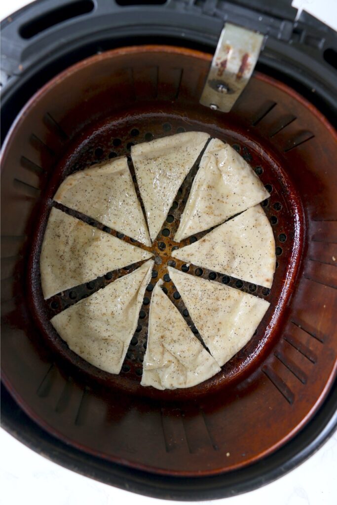 Overhed shot of pita slices in air fryer basket