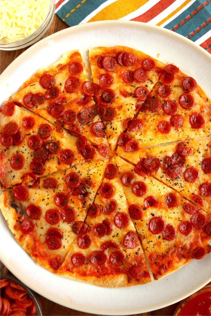 Overhead shot of sliced air fryer tortilla pizza on plate