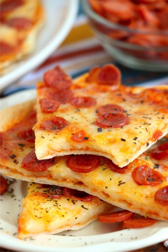 Closeup shot of air fryer tortilla pizza slices on plate with bite taken out of one slice