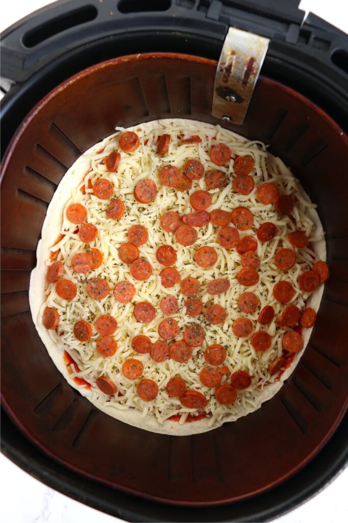 Overhead shot of uncooked tortilla pizza in air fryer basket