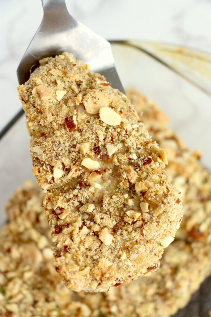 Overhead shot of almond crusted walleye filet on spatula with more filets below