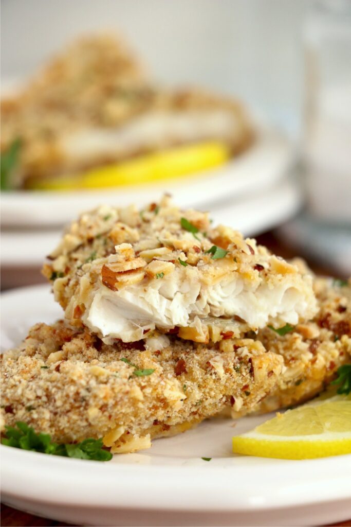Closeup shot of two almond crusted walleye filets on plate with to filet cut in half