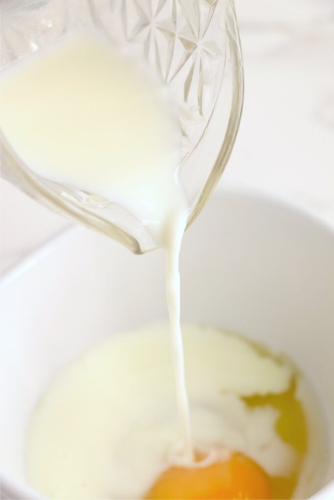 Milk being poured into bowl of eggs