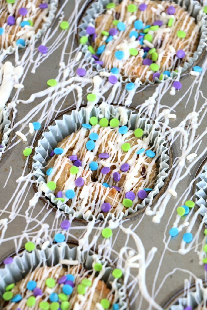 Closeup shot of chocolate chip cookies in muffin tin decorated with icing and sprinkles