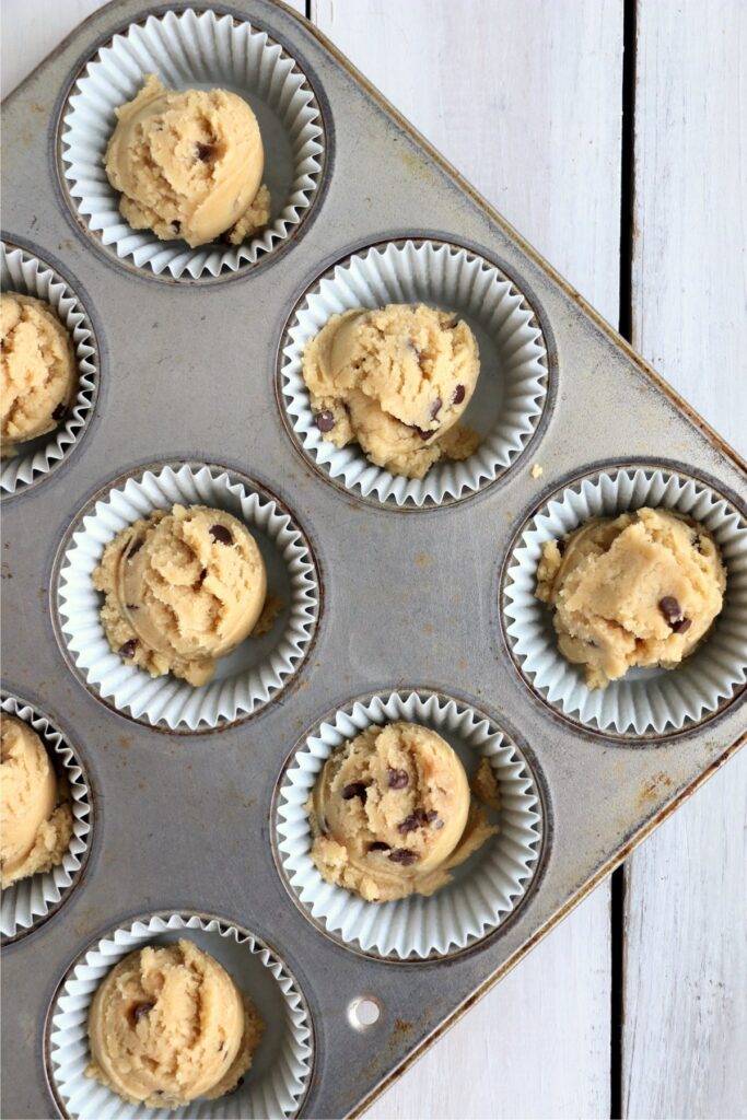 Overhead shot of scoop of chocolate chip cookie dough in muffin tins