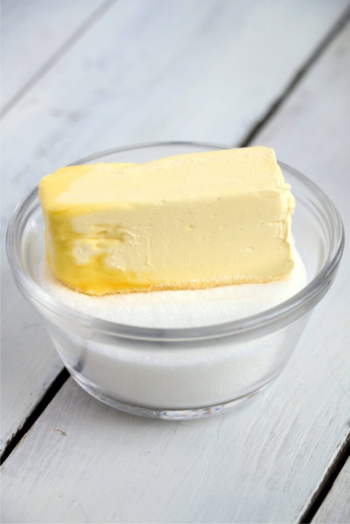 Closeup shot of stick of butter in bowl of sugar