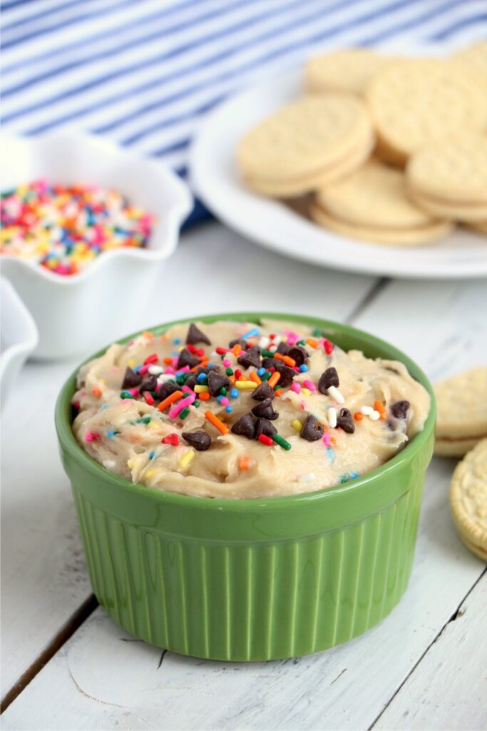 Closeup shot of rameken full of cookie dough dip with cookies in background